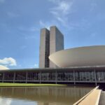 Fachada do Congresso Nacional em Brasília com iluminação ao entardecer.