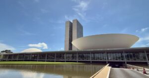 Fachada do Congresso Nacional em Brasília com iluminação ao entardecer.