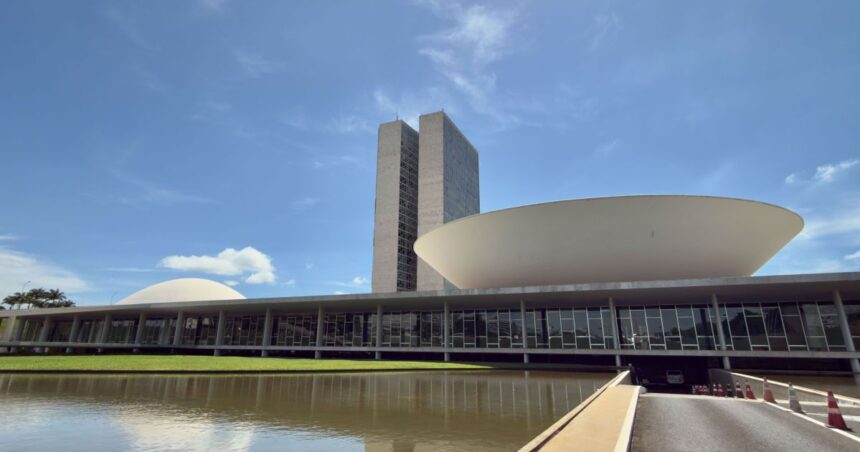 Fachada do Congresso Nacional em Brasília com iluminação ao entardecer.