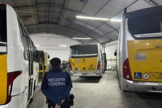 Agente da Receita Federal em garagem com ônibus do sistema municipal de São Paulo
