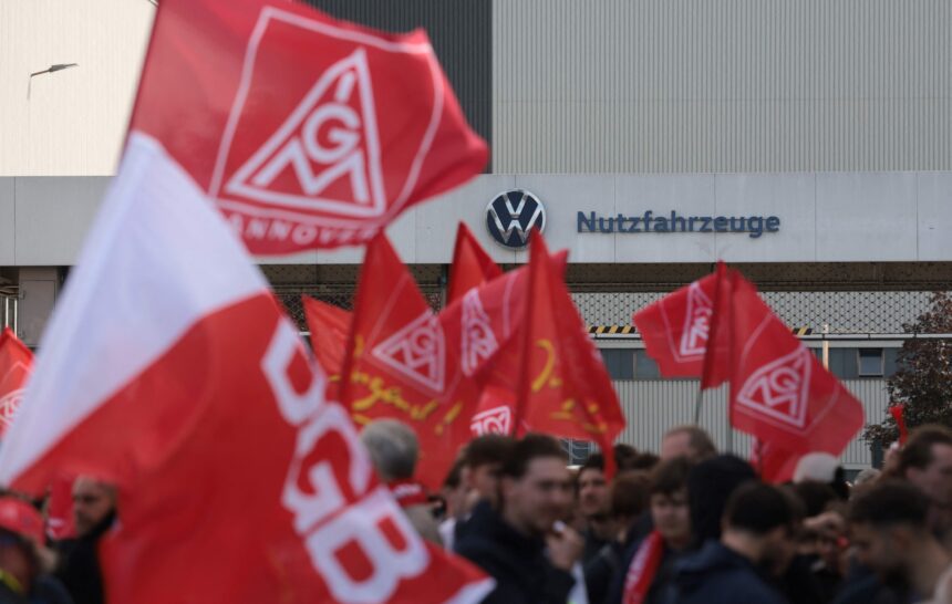 Operários com bandeiras da IG Metall, que é o sindicato de metalúrgicos da Alemanha, protestam em frente à fábrica da Volkswagen em Hanover. Trabalhadores da indústria automobilística fazem protesto em todo o país nesta segunda-feira