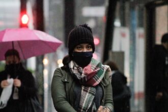Pedestres se protegem do frio e da chuva na Avenida Paulista, em SP