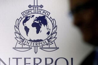 FILE PHOTO: A man passes an Interpol logo during the handing over ceremony of the new premises for Interpol's Global Complex for Innovation, a research and development facility, in Singapore September 30, 2014. REUTERS/Edgar Su//File Photo