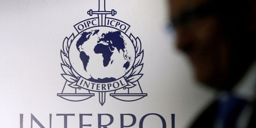 FILE PHOTO: A man passes an Interpol logo during the handing over ceremony of the new premises for Interpol's Global Complex for Innovation, a research and development facility, in Singapore September 30, 2014. REUTERS/Edgar Su//File Photo