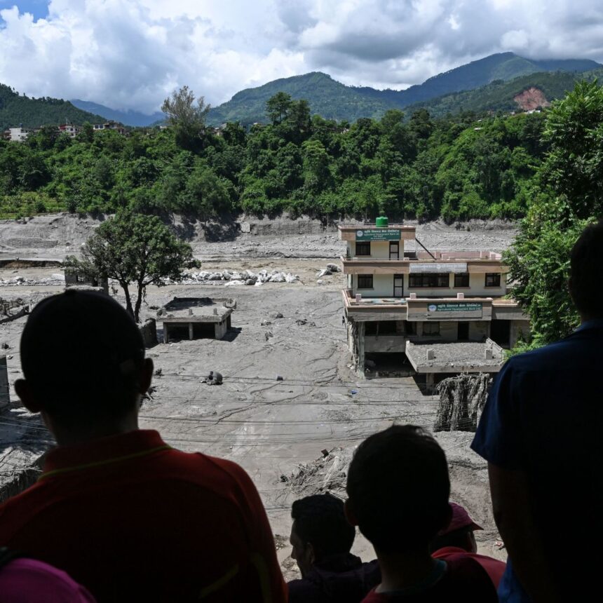 Pessoas em um telhado observam os danos causados ​​por enchentes repentinas em Trishuli, Nepal, na quinta-feira, 27 de agosto.