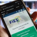 mão segura celular aberto na páfina do Fies