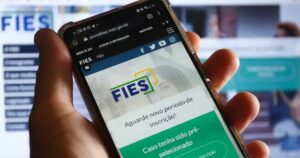mão segura celular aberto na páfina do Fies
