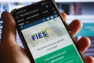 mão segura celular aberto na páfina do Fies
