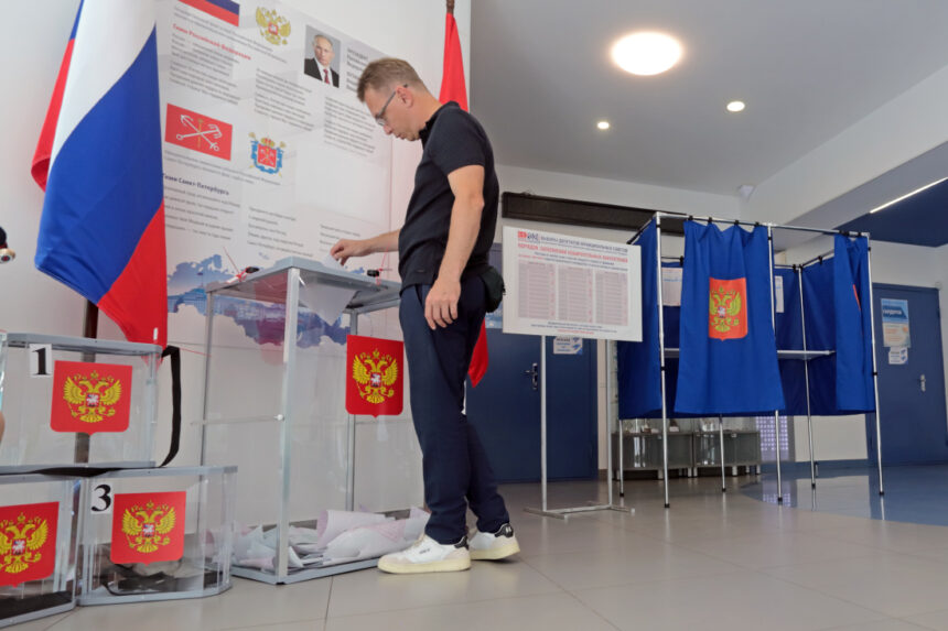 Eleitor deposita voto em urna transparente em seção eleitoral na Rússia