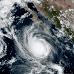 Paisagem costeira afetada por fortes ventos e mar agitado durante a aproximação de tempestade tropical.