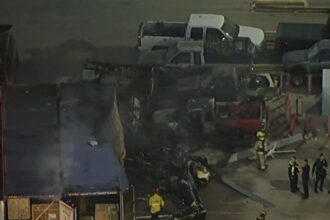 Destroços de helicóptero e veículos de emergência em área comercial de Los Angeles após queda de aeronave