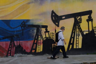 A pedestrian walks past a mural featuring oil wells in Caracas, Venezuela, Saturday, Aug 29, 2026, a day after President Donald Trump announced a deal giving the United States a stake in Venezuela’s oil reserves. (AP Photo/Pedro Mattey)