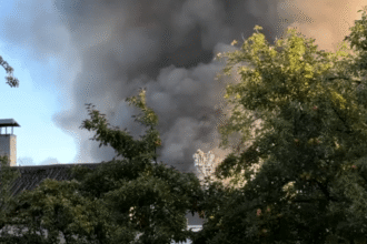 Coluna de fumaça subindo de área industrial após queda de destroços de drone em Kiev
