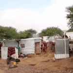 Abrigos no acampamento de Al-Bireen; crianças de pé ao redor
