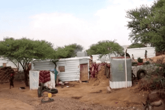 Abrigos no acampamento de Al-Bireen; crianças de pé ao redor
