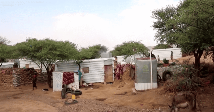 Abrigos no acampamento de Al-Bireen; crianças de pé ao redor
