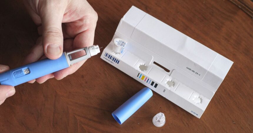 Frasco de medicamento e caneta aplicadora em ambiente neutro