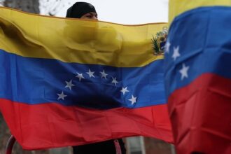 Pessoas seguram bandeiras da Venezuela em frente ao Tribunal Federal Daniel Patrick Moynihan, antes da audiência de acusação do ditador da Venezuela, Nicolás Maduro, e da primeira-dama, Cilia Flores, em 5 de janeiro de 2026, na cidade de Nova York.