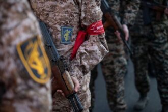 Integrantes armados do Corpo da Guarda Revolucionária Islâmica do Irã seguram fuzis AK-47 e participam de uma manifestação militar no centro de Teerã