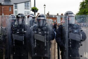 Membros da polícia de choque seguram se posicionam enquanto tumulto continua em Ballymena, Irlanda do Norte