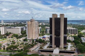 Sede do Banco Central aparece em imagem tirada de longe. O edifíco possui duas colunas brancas e um centro mais escuro, ficando em destqqeu em meio ao resto da cidade que tambpem aparecem na foto