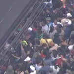 Movimento de pedestres e veículos em rua comercial de São Paulo