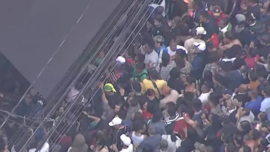 Movimento de pedestres e veículos em rua comercial de São Paulo